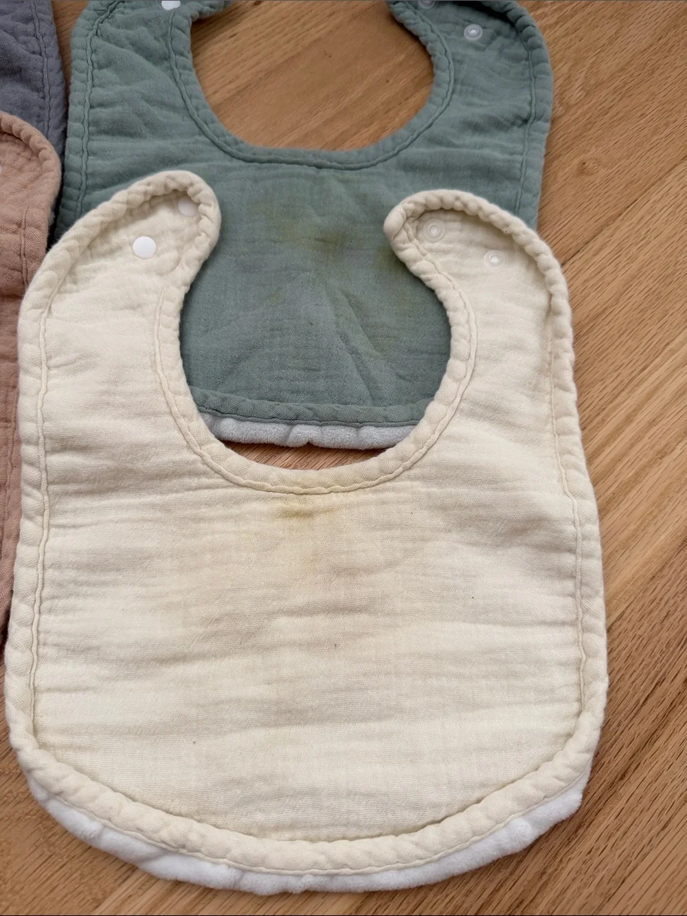 Bundle of muslin baby bibs in earthy colors
